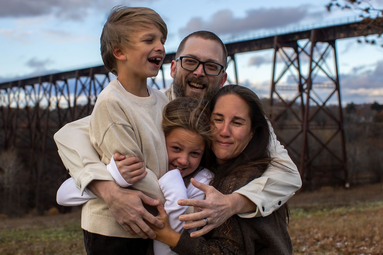 Candid family moments captured against industrial bridge backdrop.