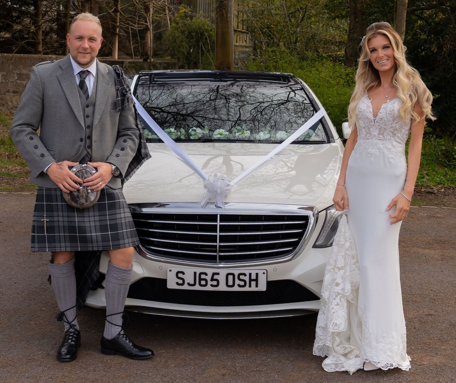 bride and groom standing alongside the Mercedes wedding car