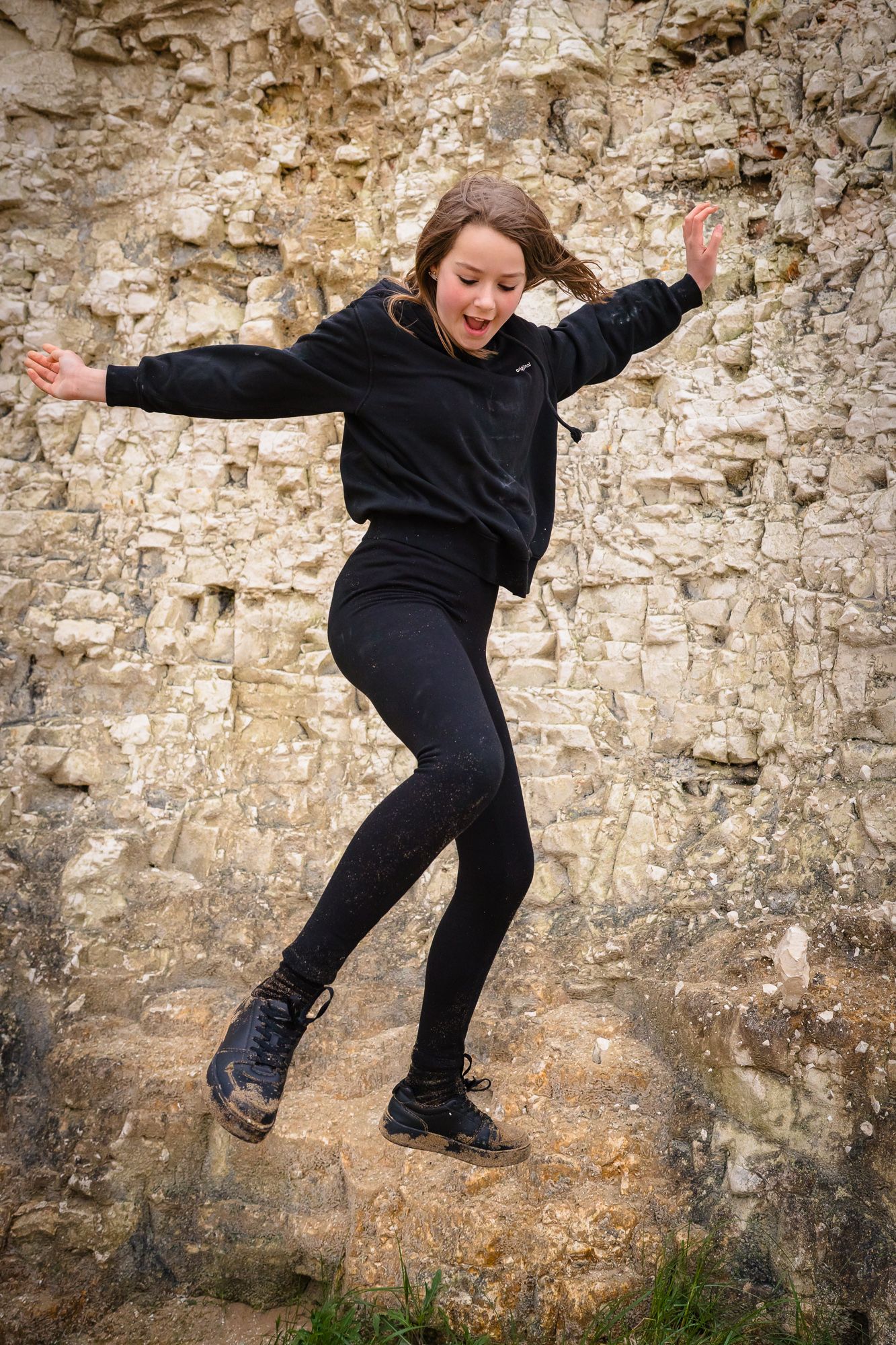 Action shot of a girl jumping from the rocks at a family beach photo session, Kent.