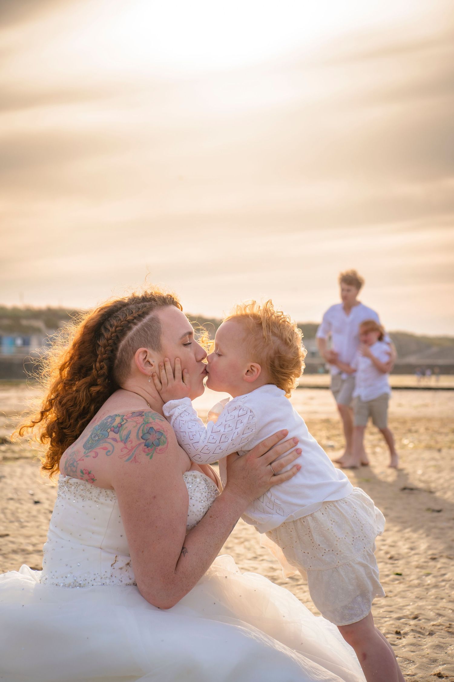 Candid photo of the whole family at a special family photo session with father and son walking behind a mother and daughter having a kiss.