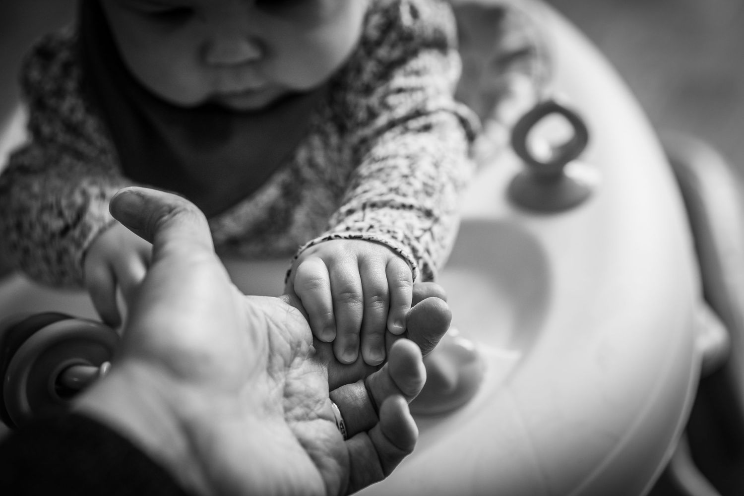 A baby reaching out to hold her Mother's hand, b&w image that shows emotion and feeling.