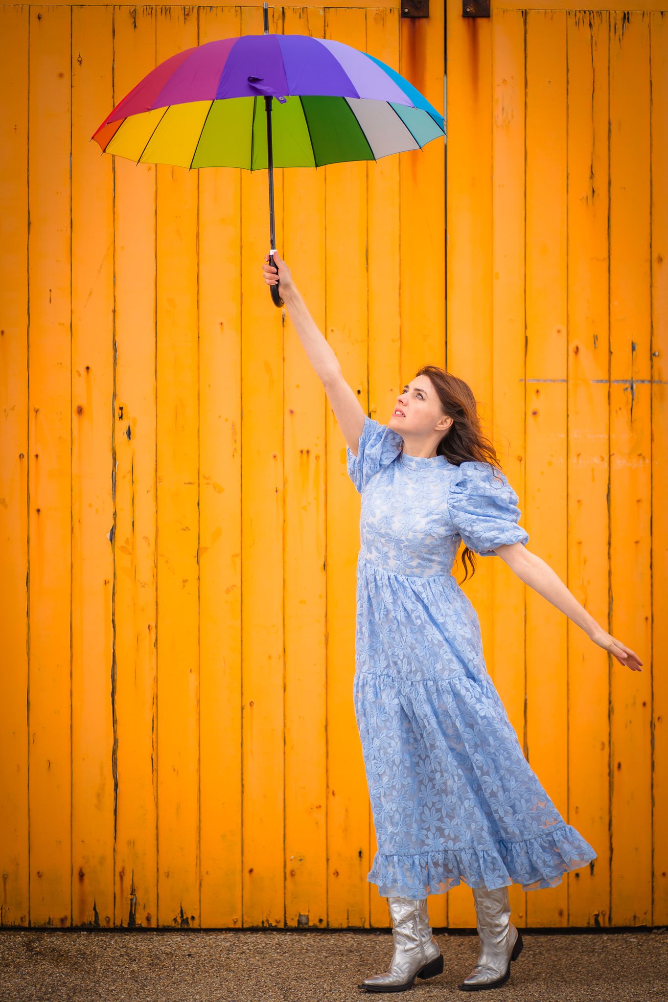 Girl in blue dress with rainbow coloured umbrella, floating away with an orange backdrop. Taken in Margate Kent.