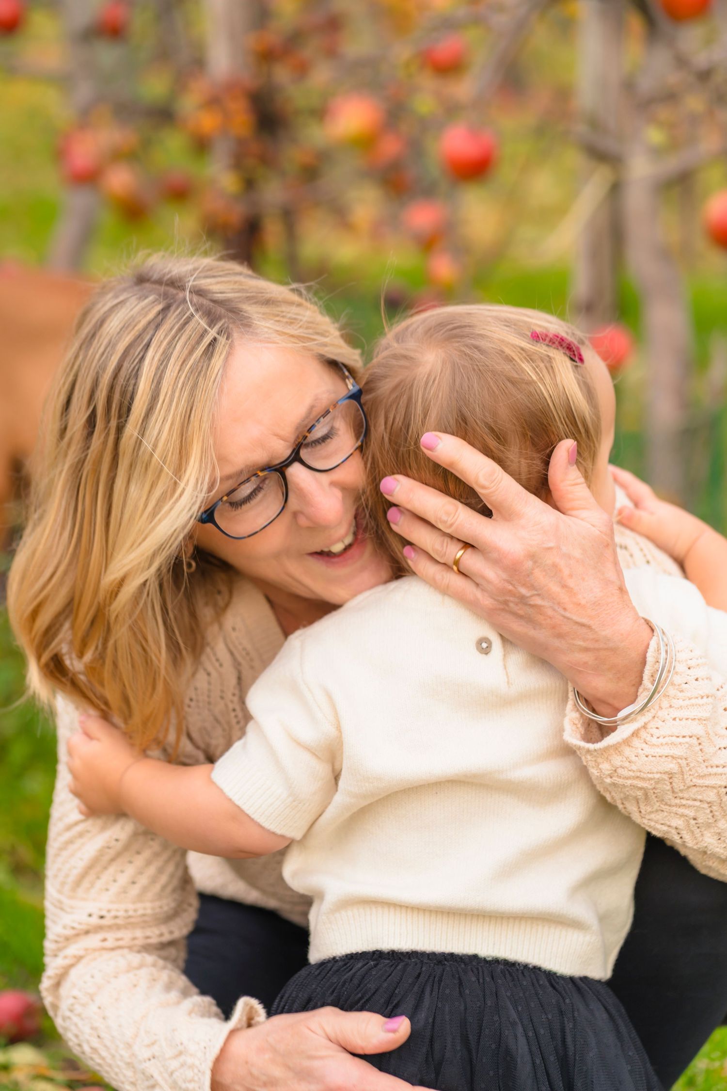 A grandmother and granddaughter having a cuddle in an apple orchard.
