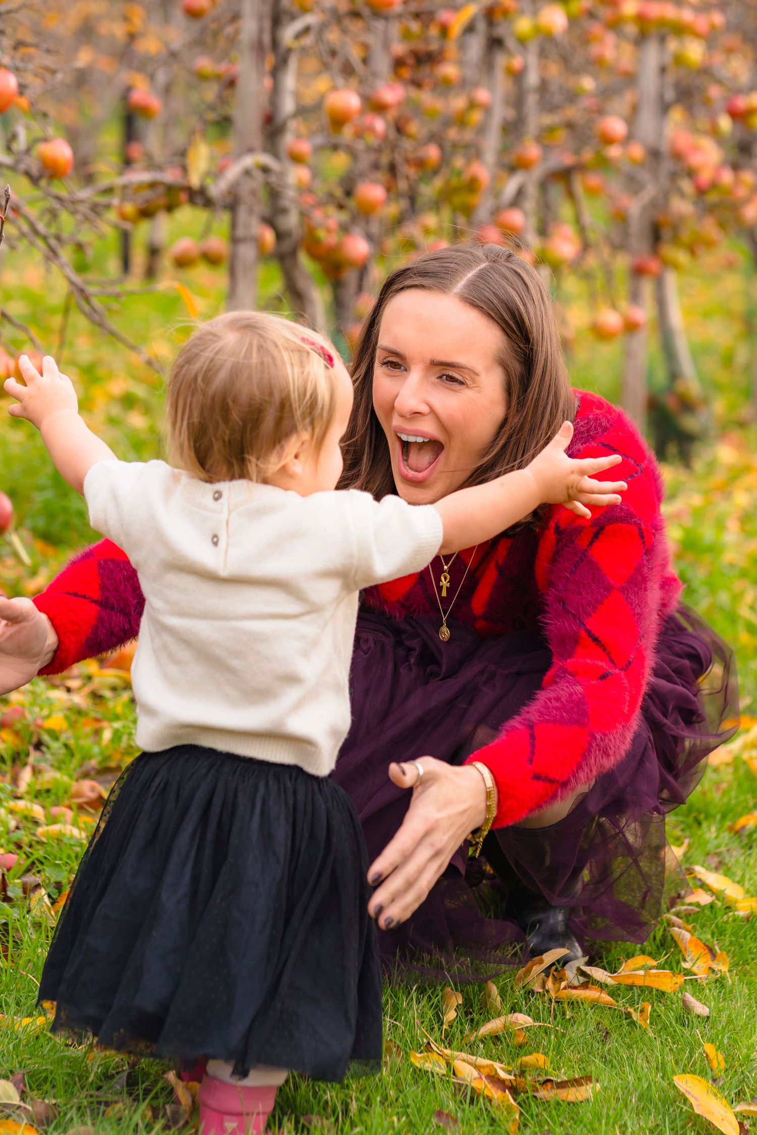 A toddler running towards her mother who is bent down with open arms.