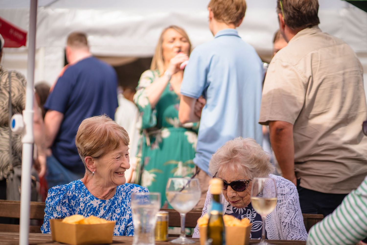 Two elderly grandmother's having a chat and a giggle at a family celebration, candid and unposed, real emotions that are to remember forever