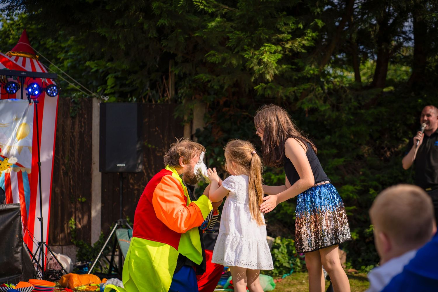 Two children putting a cream pie in the clowns face at a celebration event, candid capture from shorely a memory.