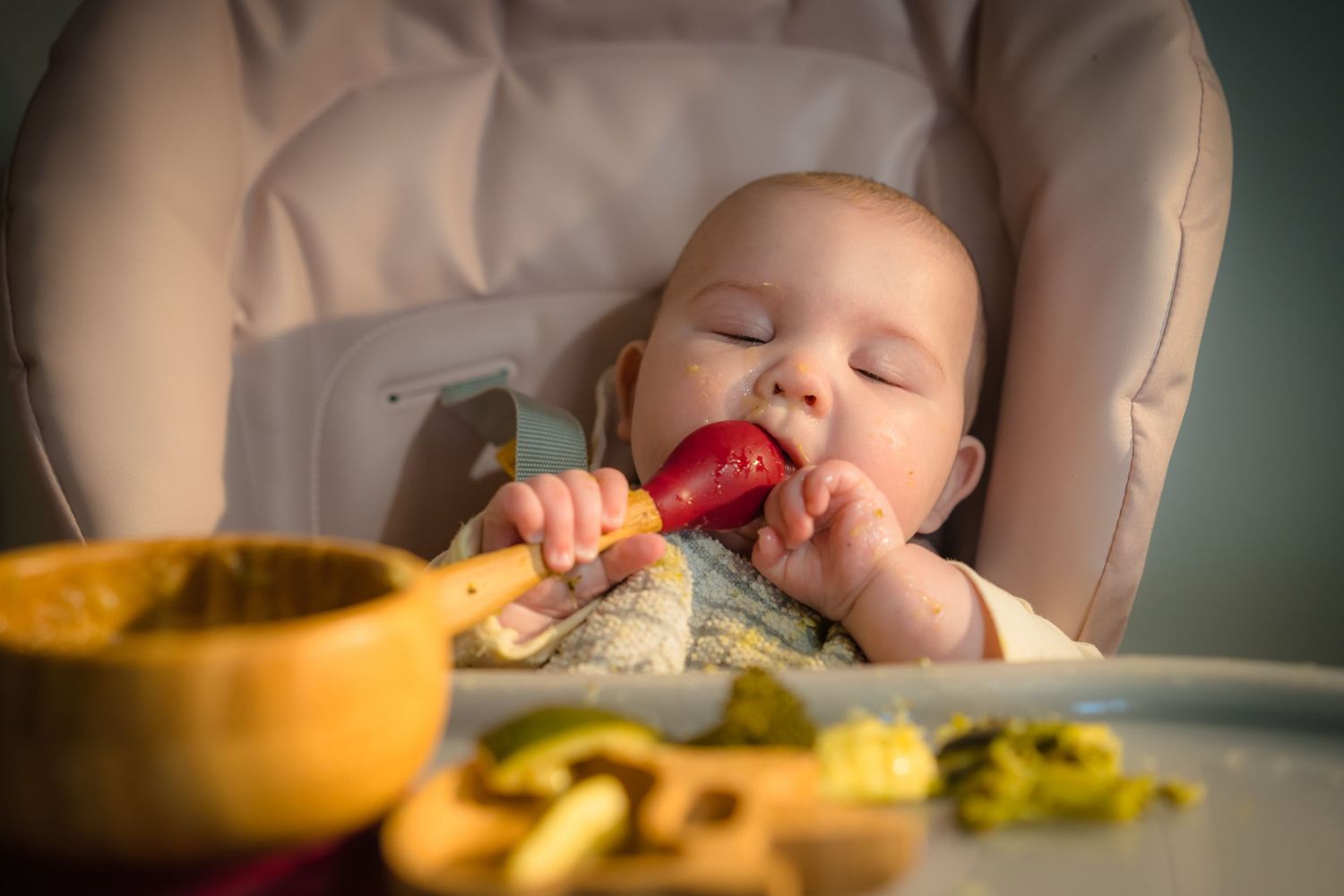 A baby feeding themselves their baby food, In home candid and unposed photo session.