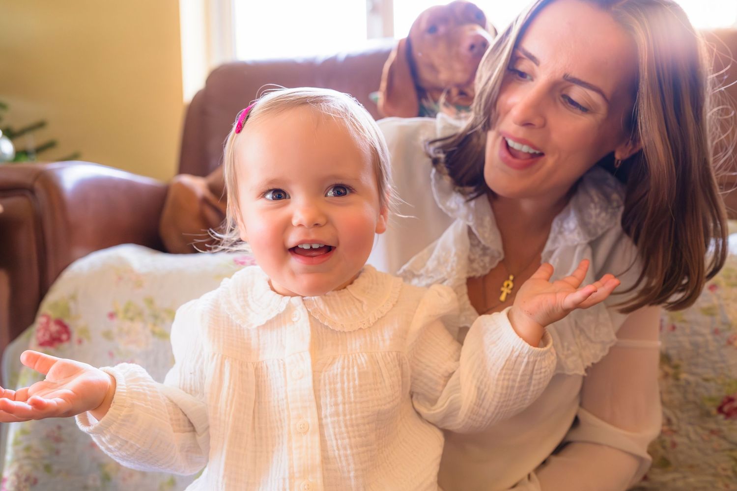 mother, daughter and dog behind, smiling and singing together with sun rays peeking in.