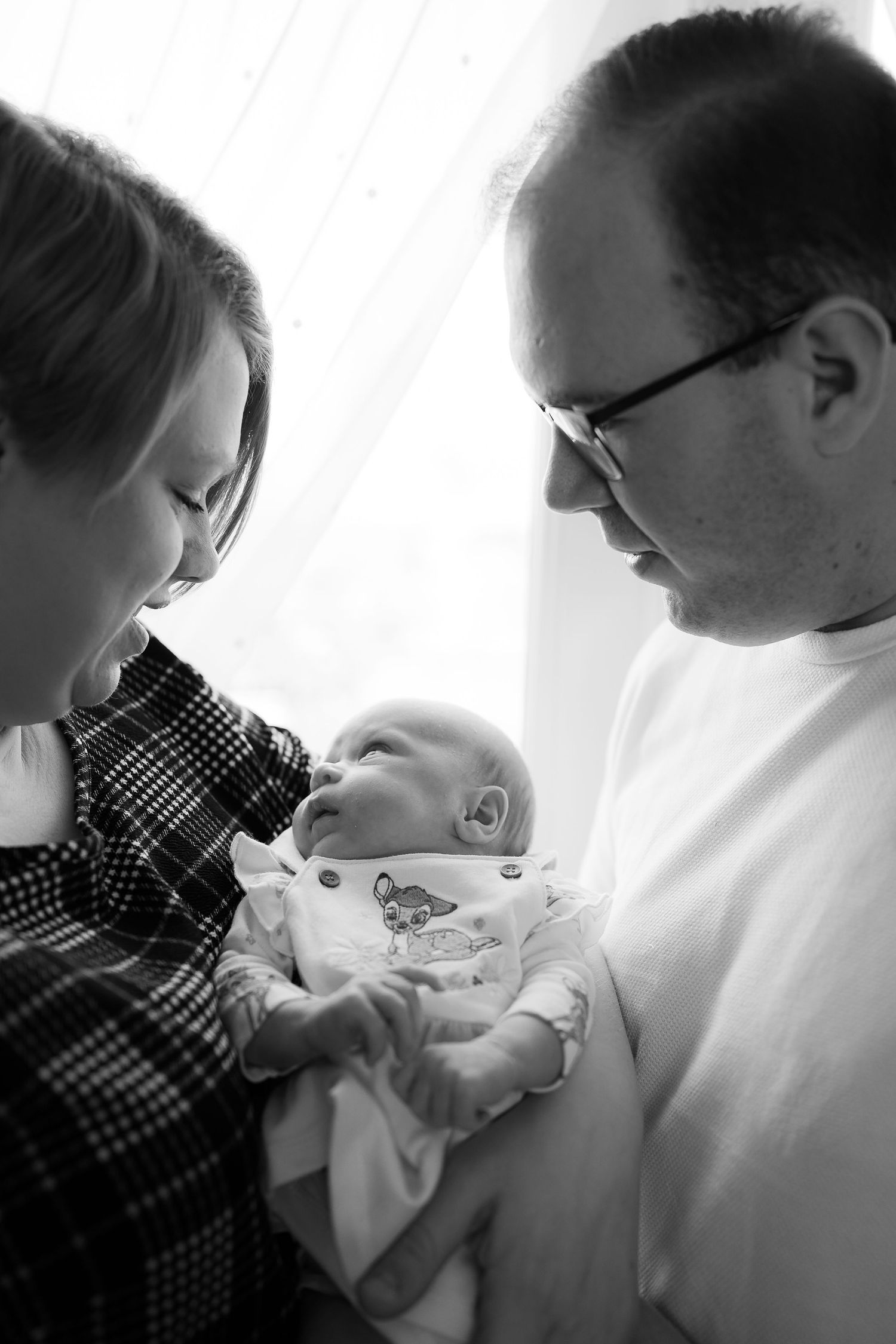 in home photo session taken in front of a well lit window. Black and white showing emotion of having a new baby to love in Kent.