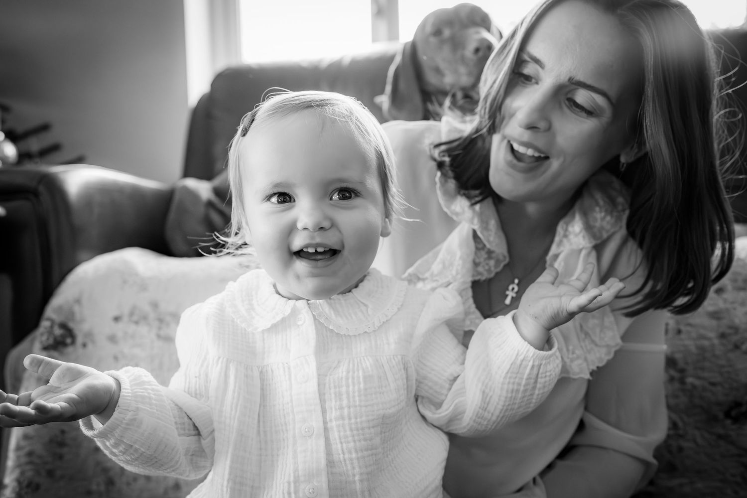 Mother, daughter and dog behind, smiling and singing together with sun rays peeking in. Black and White to show the emotion