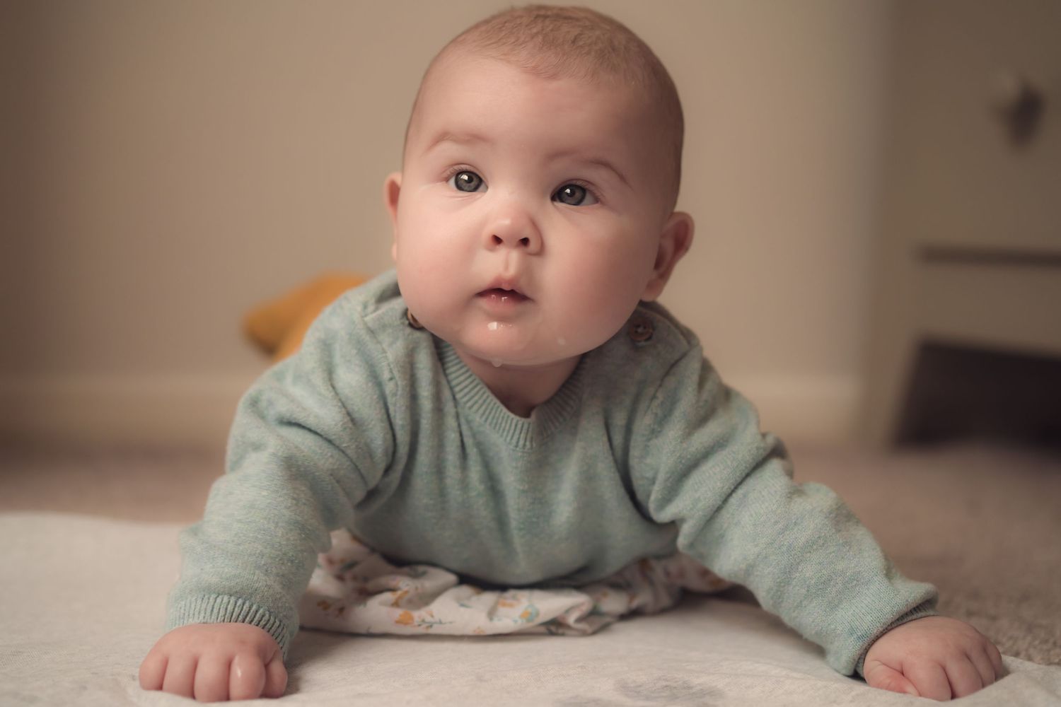Soft and delicate baby portrait of a baby laying on their tummy and holing themselves up at an in home family photo session, unposed.