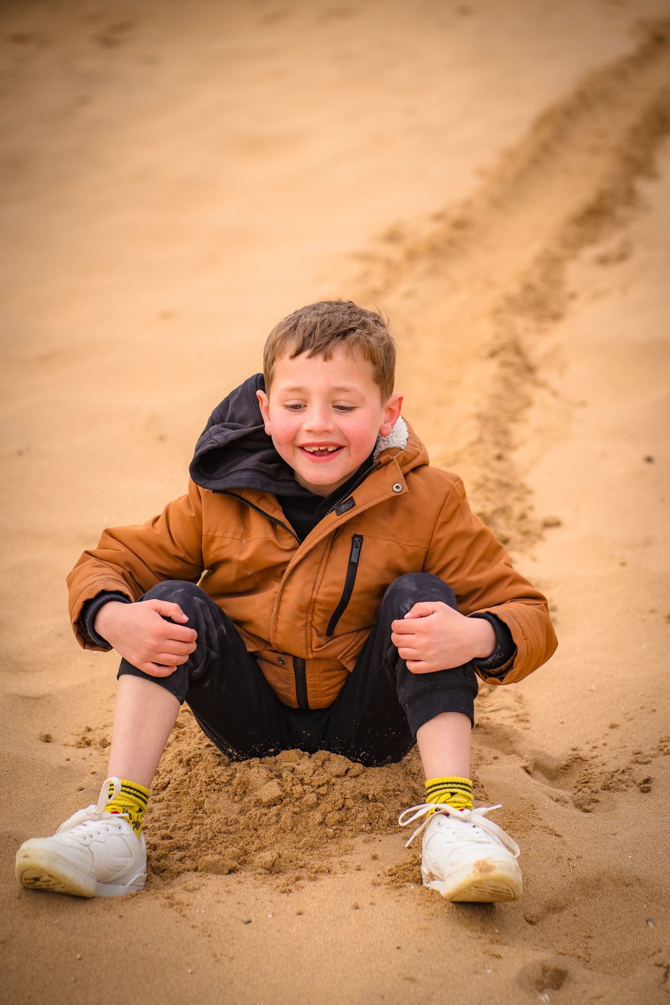 Young boy sliding down the sand on a family photo session at Botany Bay, Margate with Shorely a Memory Photography, Kent.