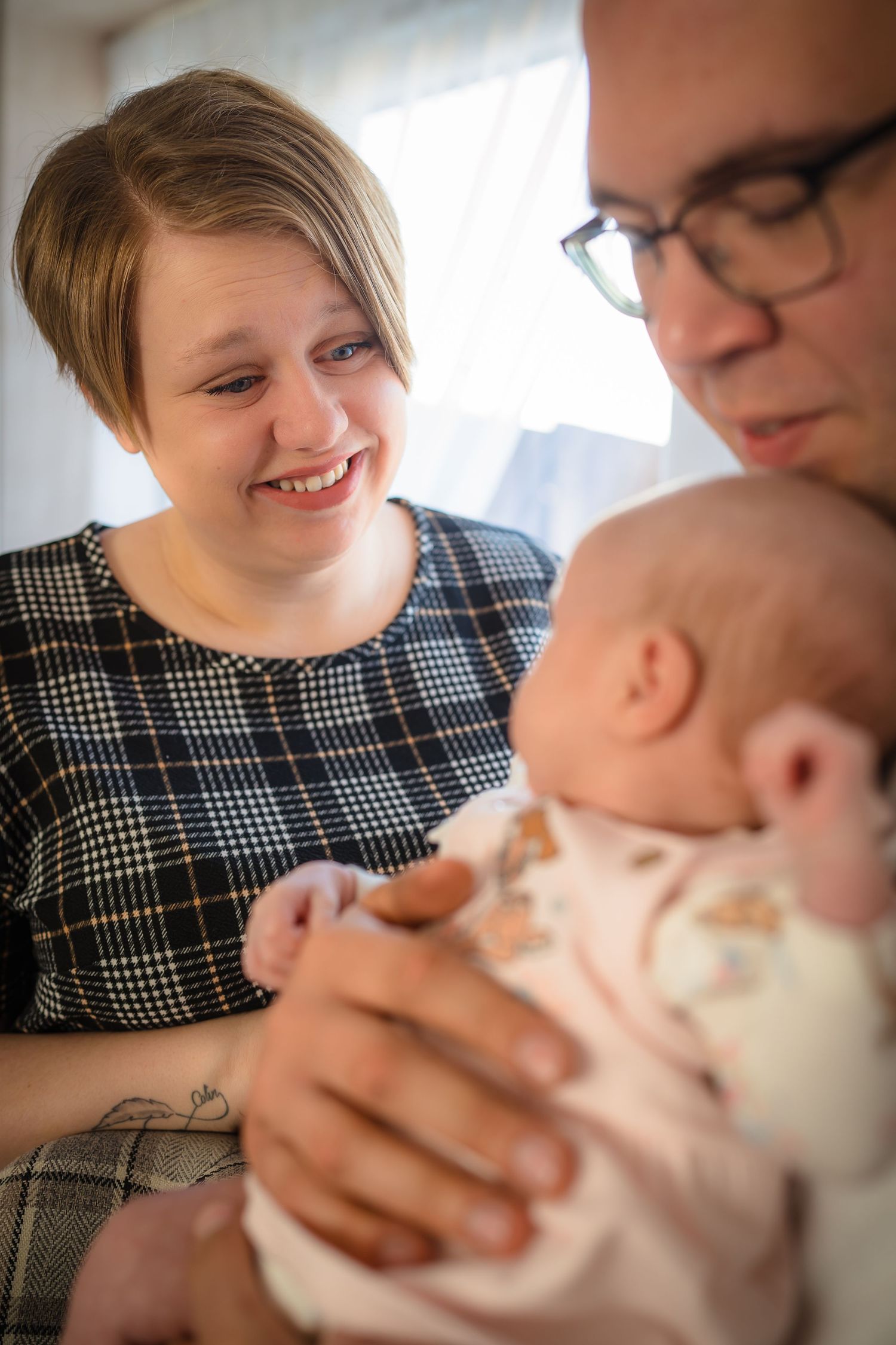 A mother smiling at her baby whilst being held by the father, in home family photo session with Shorely a memory photography, Margate.