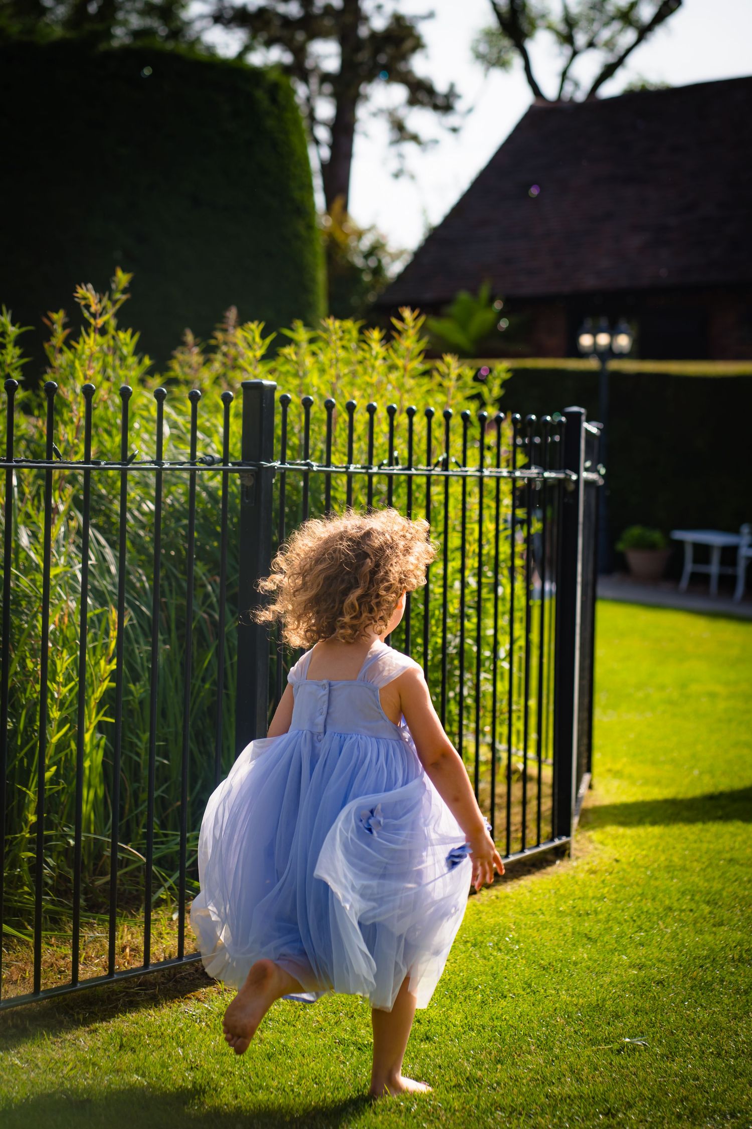 A wild haired girl running through a Kent park in a blue dress and barefoot.
