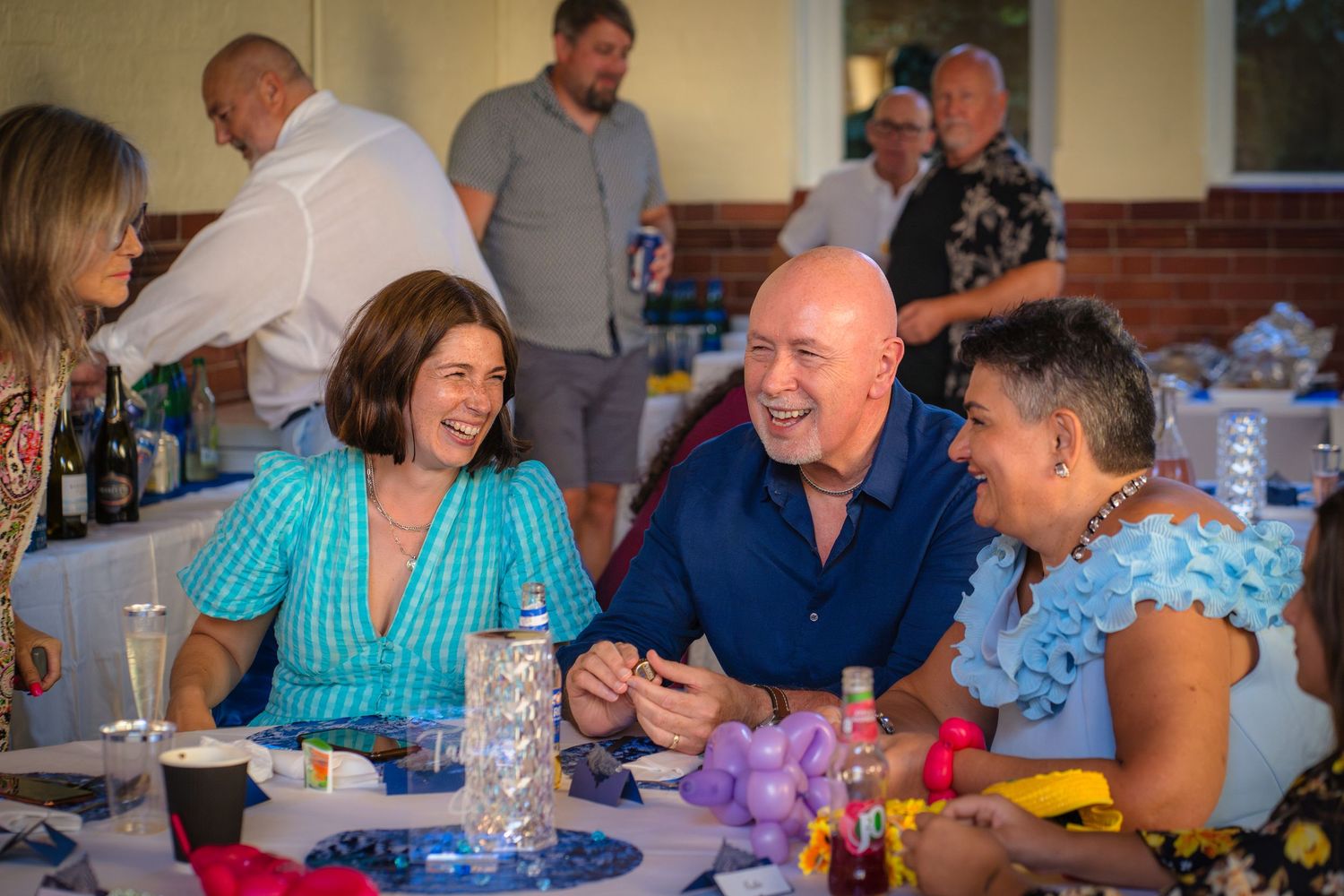 Sharing a moment, a group of people laughing at a table whilst enjoying a family gathering with Shorely a memory photography