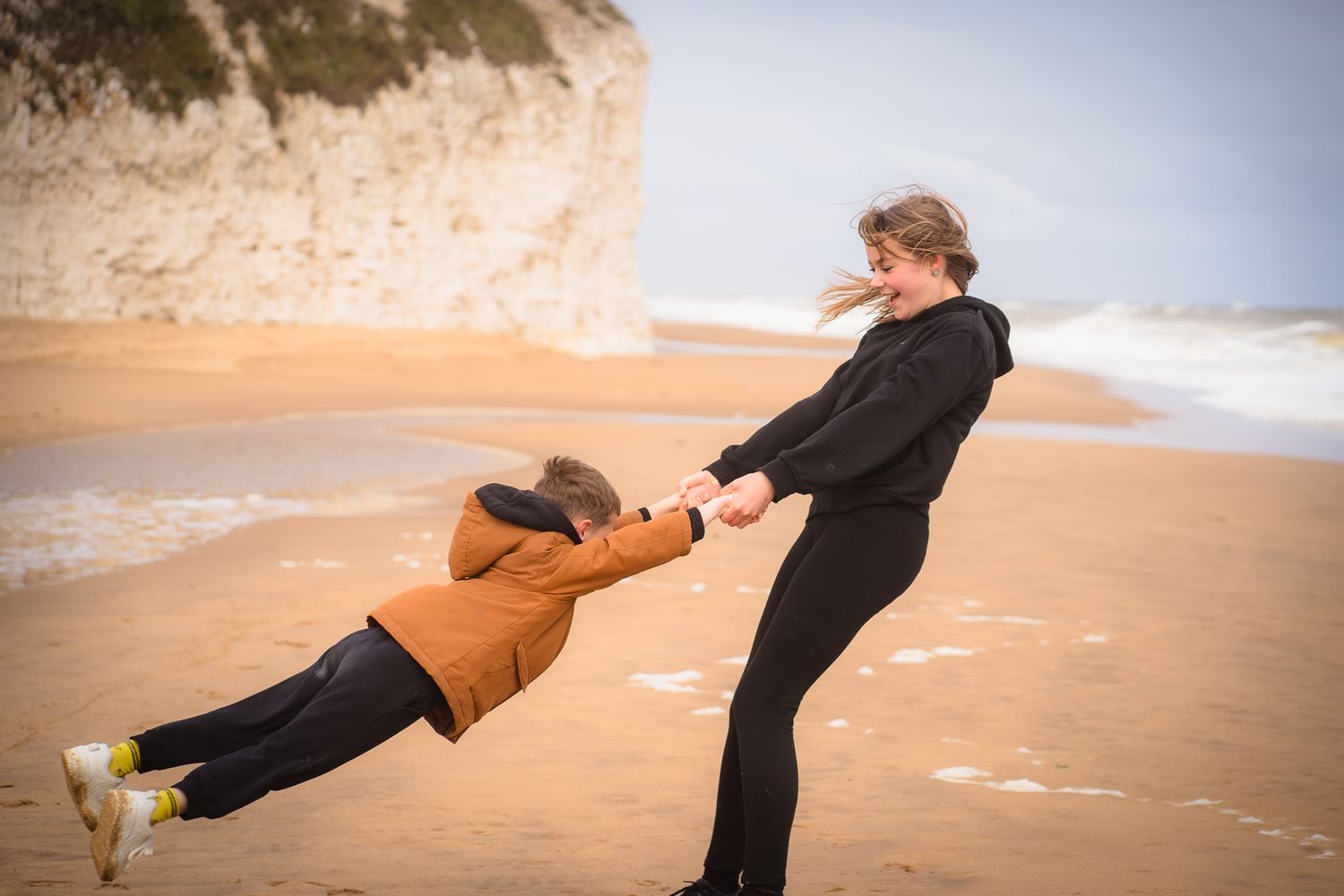 Siblings spinning each other around on the sand on a family photo session at Botany Bay, Margate with Shorely a Memory Photography, Kent.