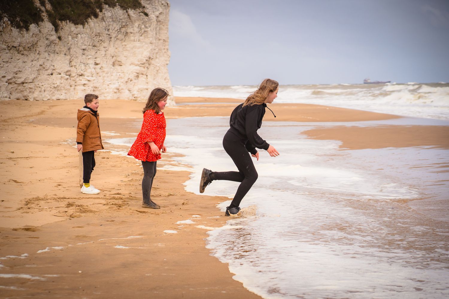 three siblings running into the sea at a wintery beach photo session with shorely a memory, Botany Bay.