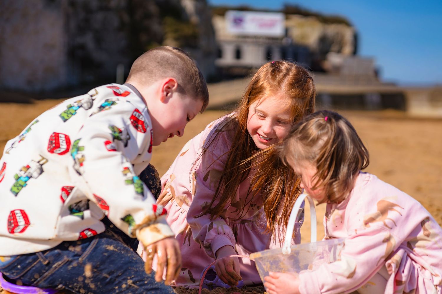 3 children building sandcastles near palm bay in Thanet, laughter and candid moments are the best.