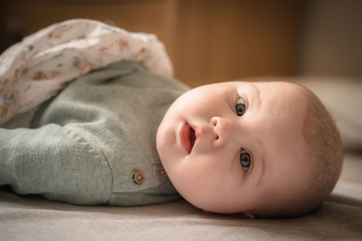 Soft Portrait of a baby lying on the floor with lovely green and soft tones to show the softness of a baby in home session.