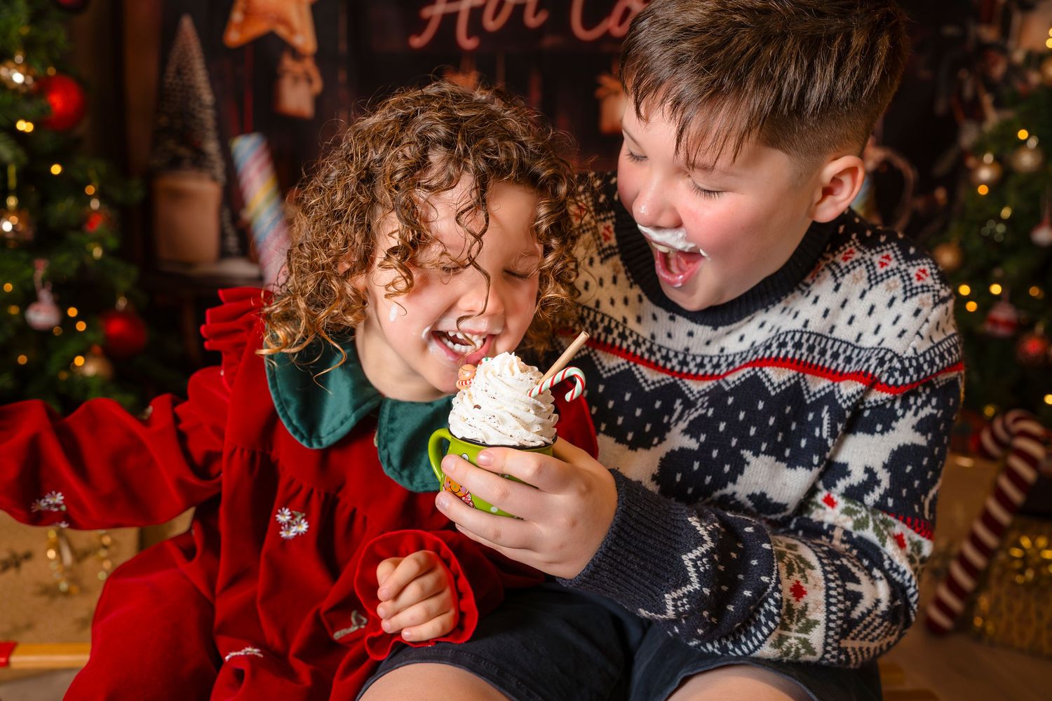 Brother and Sister sharing a cup of cocoa with cream on their faces at their Christmas mini photo session with Shorely a Memory, Kent.
