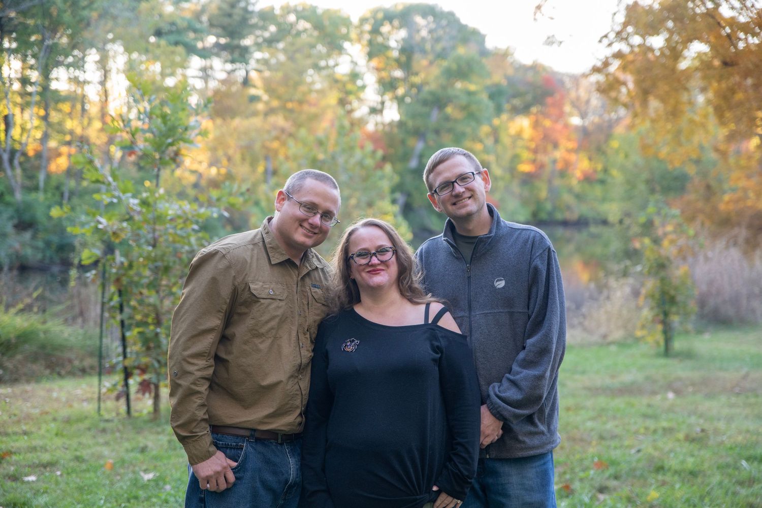 Small group poses casually together during outdoor fall family photoshoot.
