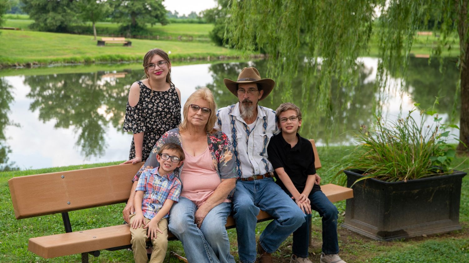 Extended family portrait session at a park with willow trees and wooden benches.