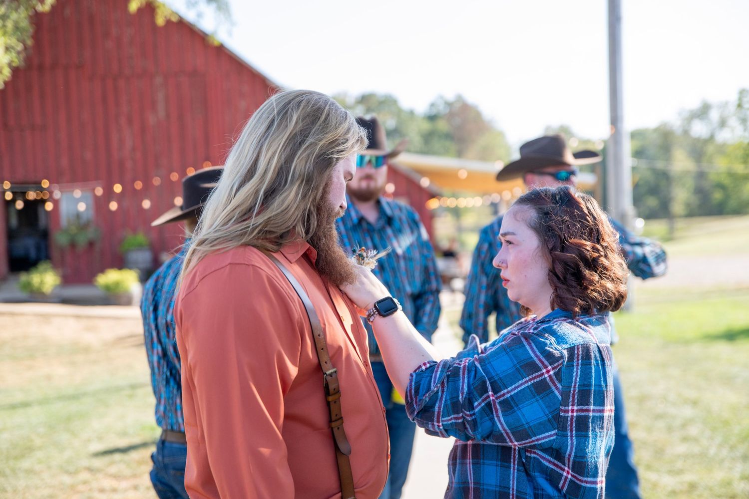 Outdoor scene with red barn in background during wedding day preparations.