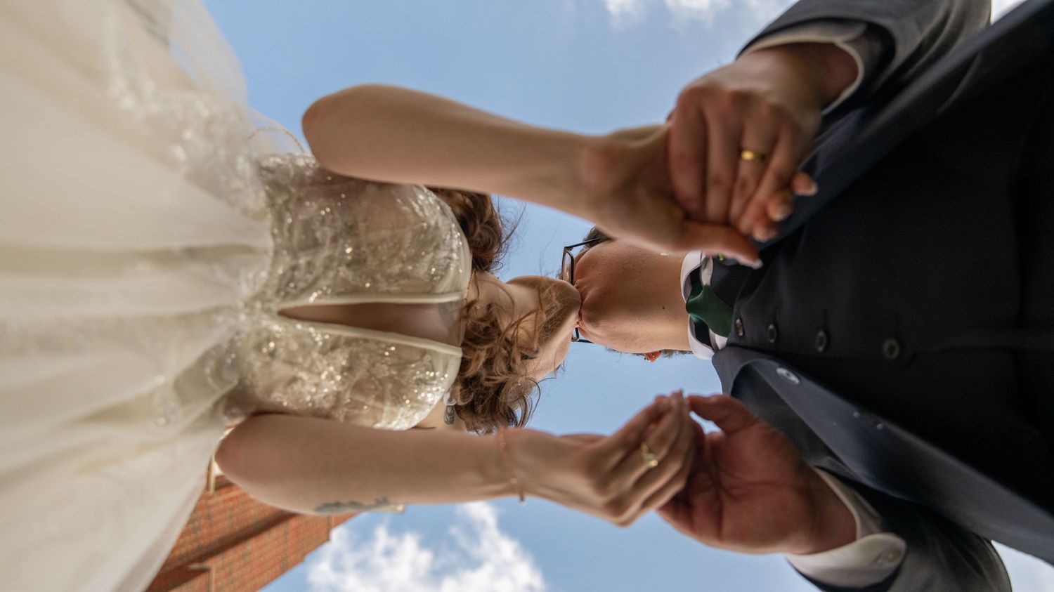 Close-up wedding portrait details against bright blue sky background.