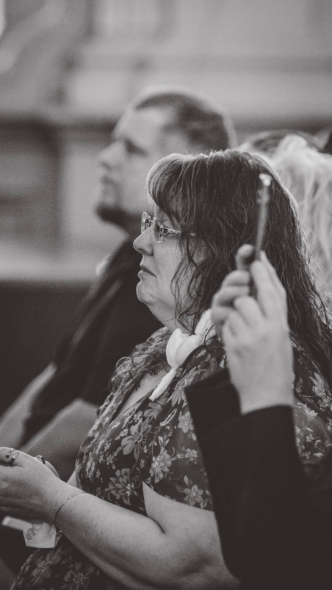 Black and white photo of wedding guests watching the ceremony in church pews.