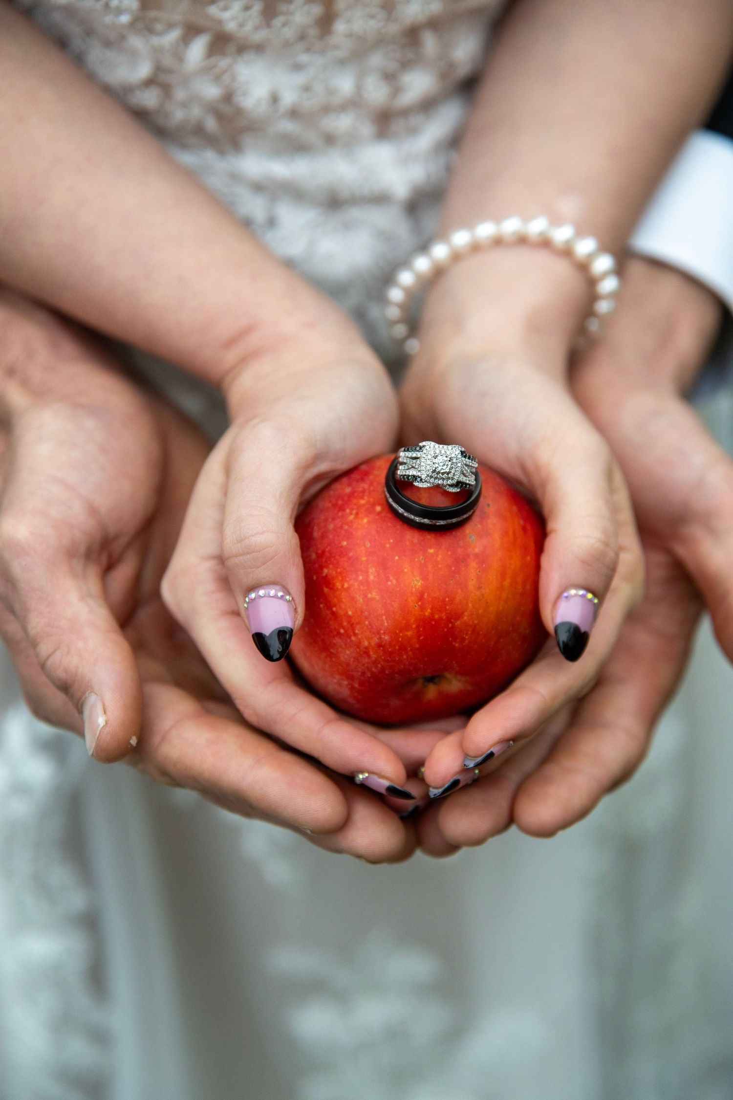 Close-up of manicured hands holding red apple with wedding ring detail.