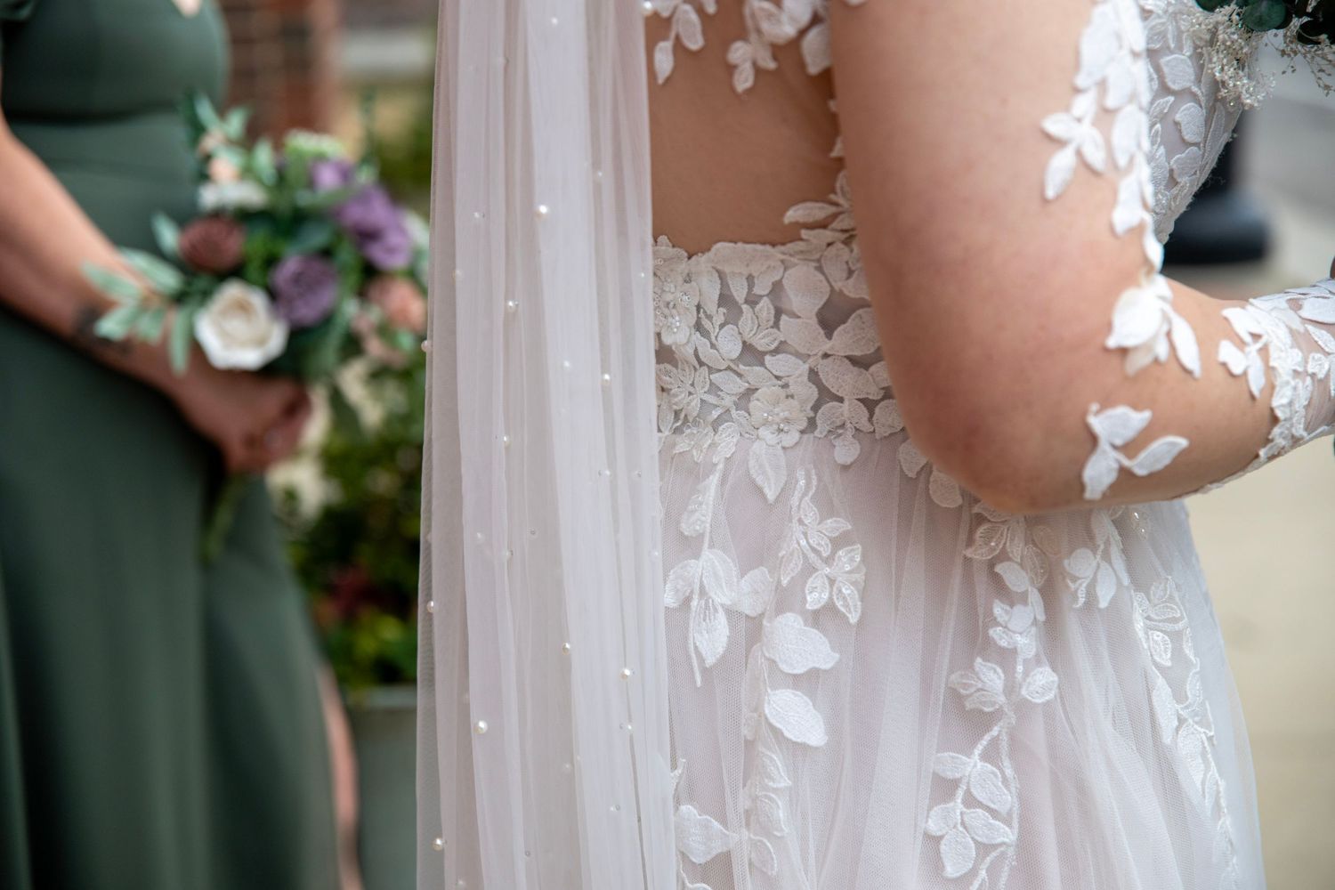 Close-up detail of delicate floral lace appliques on a wedding dress sleeve.