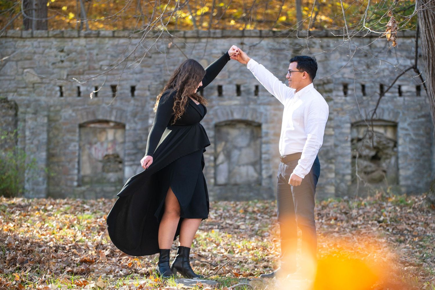 Stone wall and autumn leaves create romantic backdrop for couple's photos.