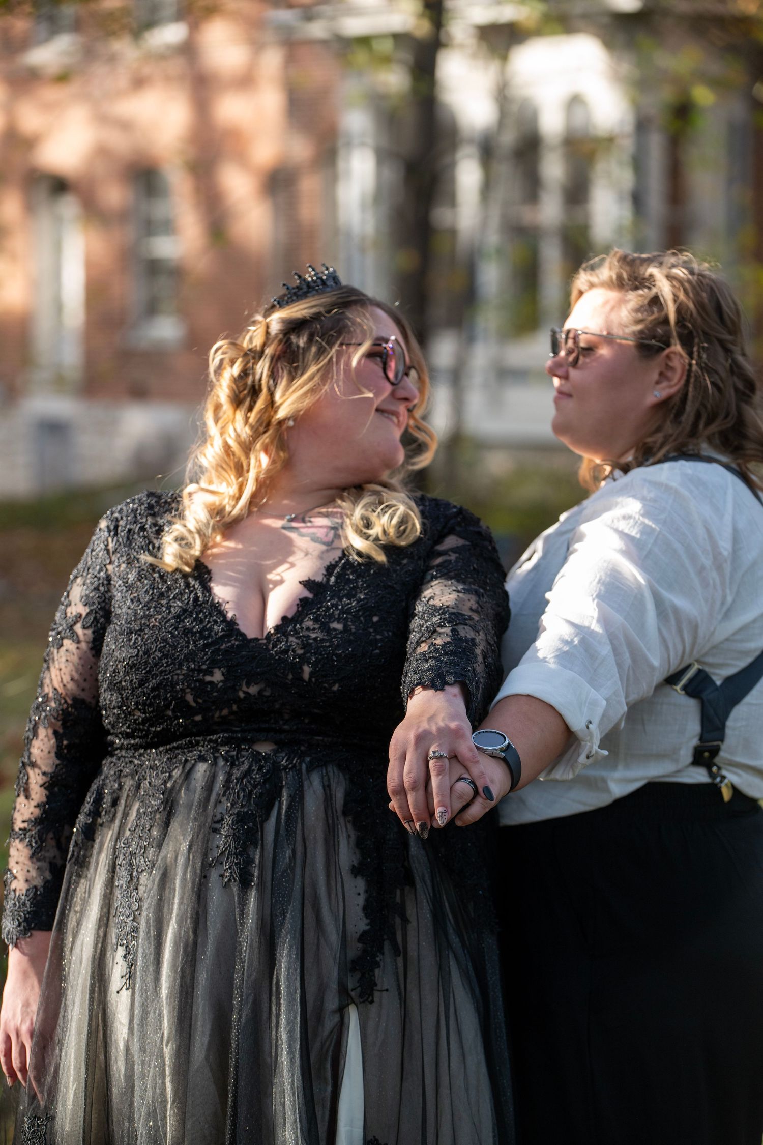 Two people in contrasting black and white formal wear embrace outdoors.