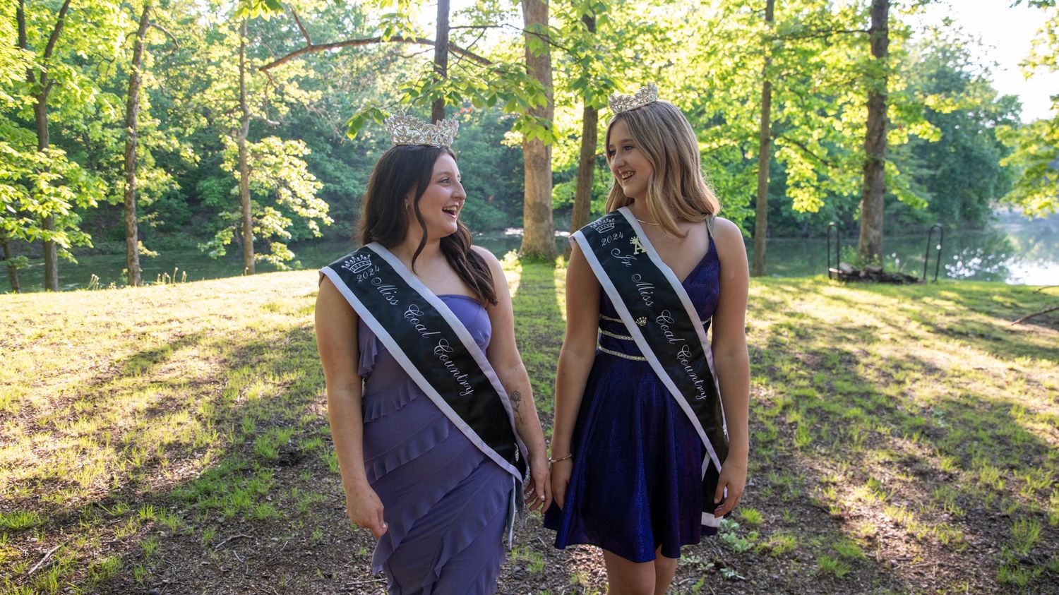 Contestants pose in formal attire during an outdoor photo session with trees in background.