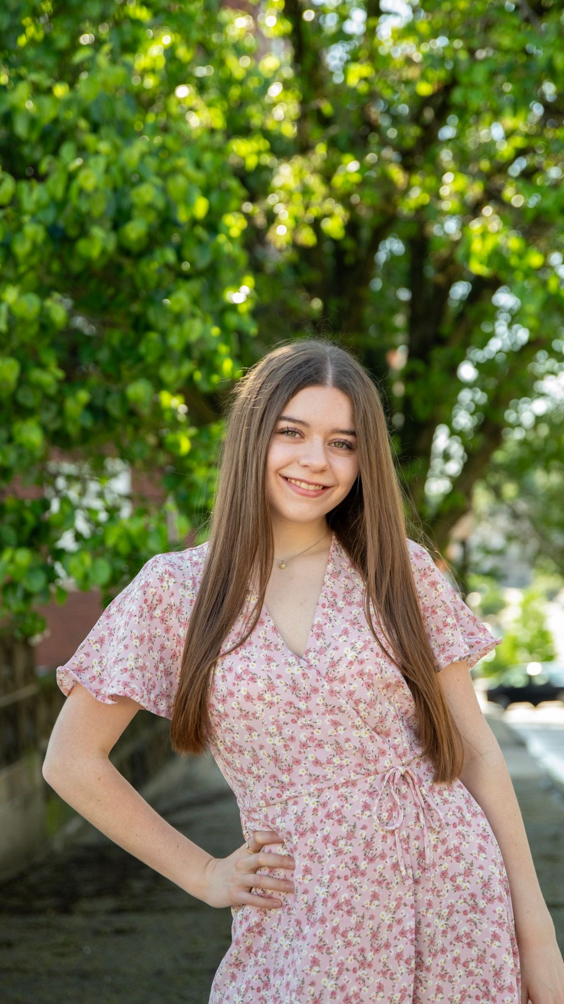 Outdoor portrait series in a pink floral dress with natural garden backdrop.