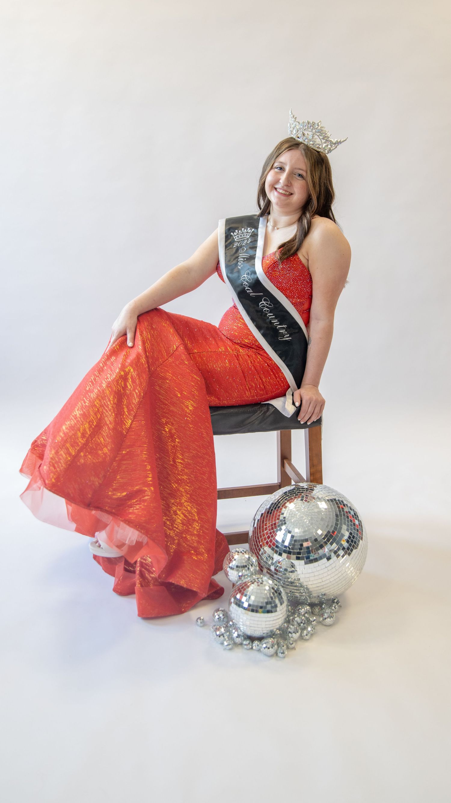 A photo series featuring a red formal dress and disco balls against a white studio backdrop.