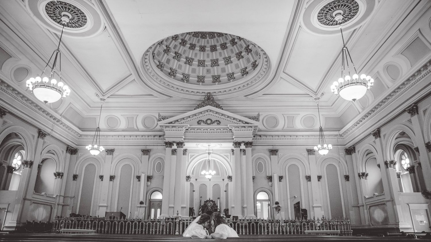 Black and white panoramic photograph of a grand historic ballroom interior with ornate architectural details.