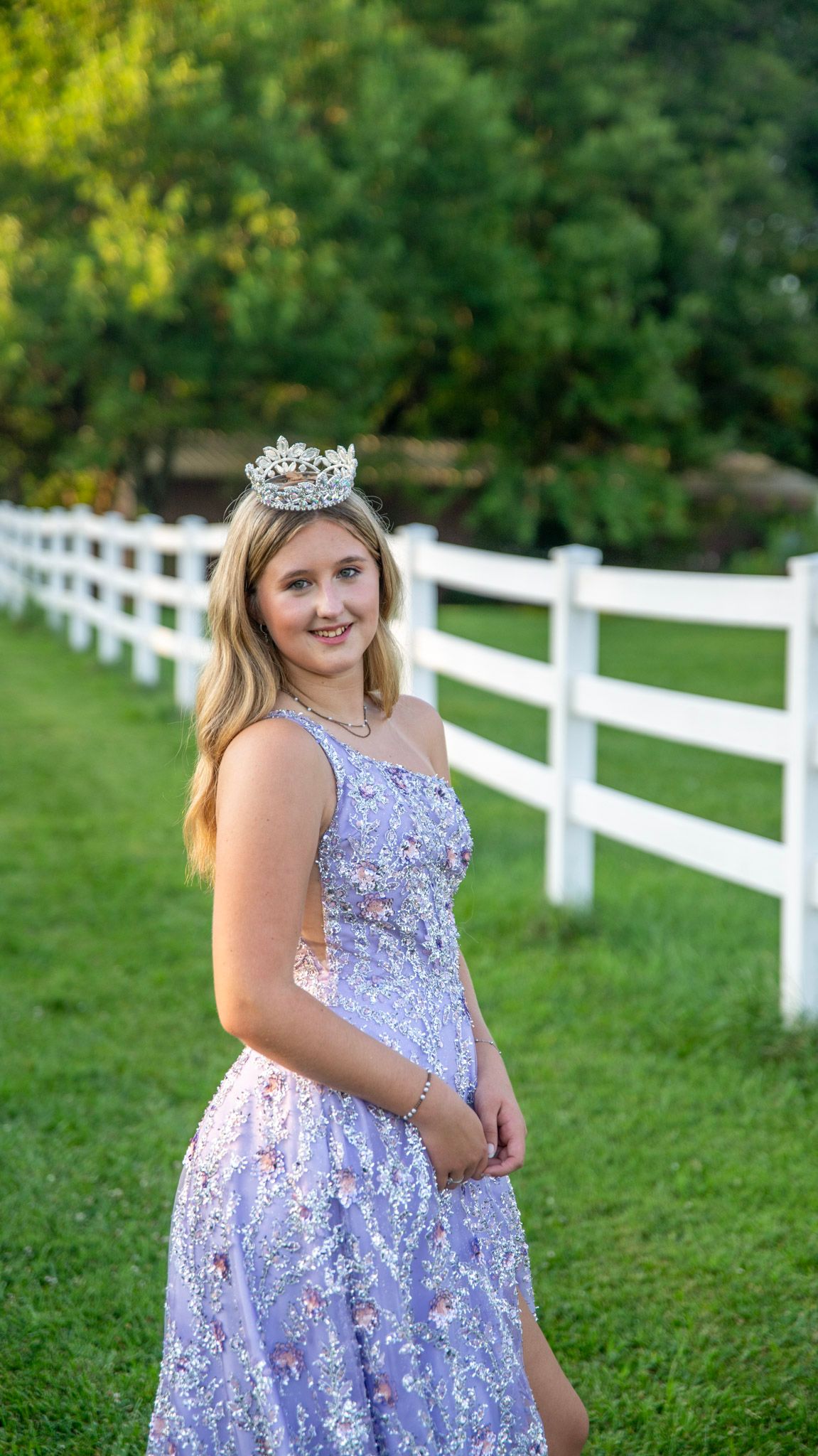 A lavender sequined dress sparkles in natural lighting by a white fence.