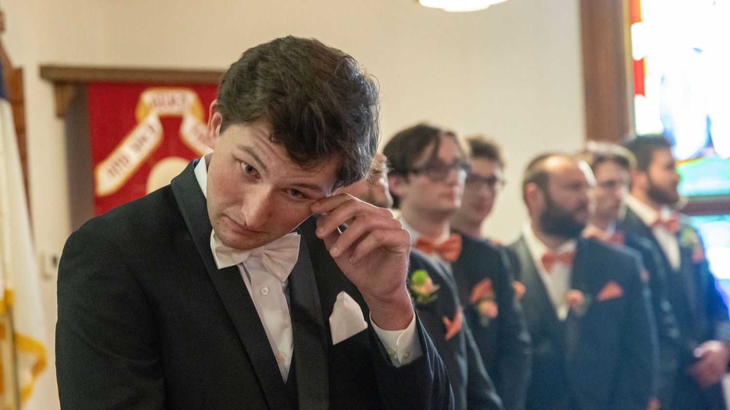 Groomsmen in formal attire standing together at a wedding venue.
