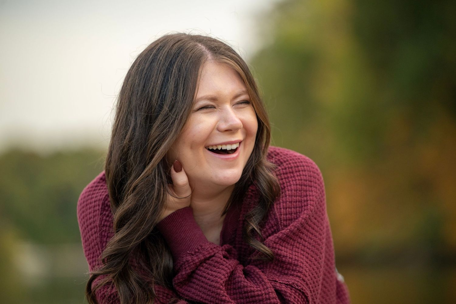 A candid portrait session on a wooden deck with fall colors in the background.