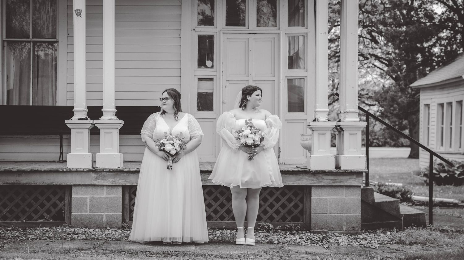 Black and white photo of people in formal attire standing in front of a historic white house.