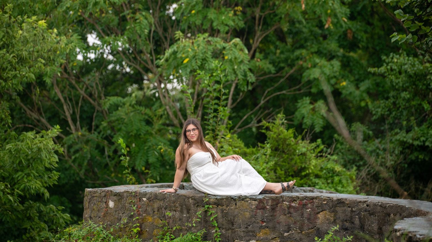 Panoramic view of stone wall and greenery during outdoor photo session.