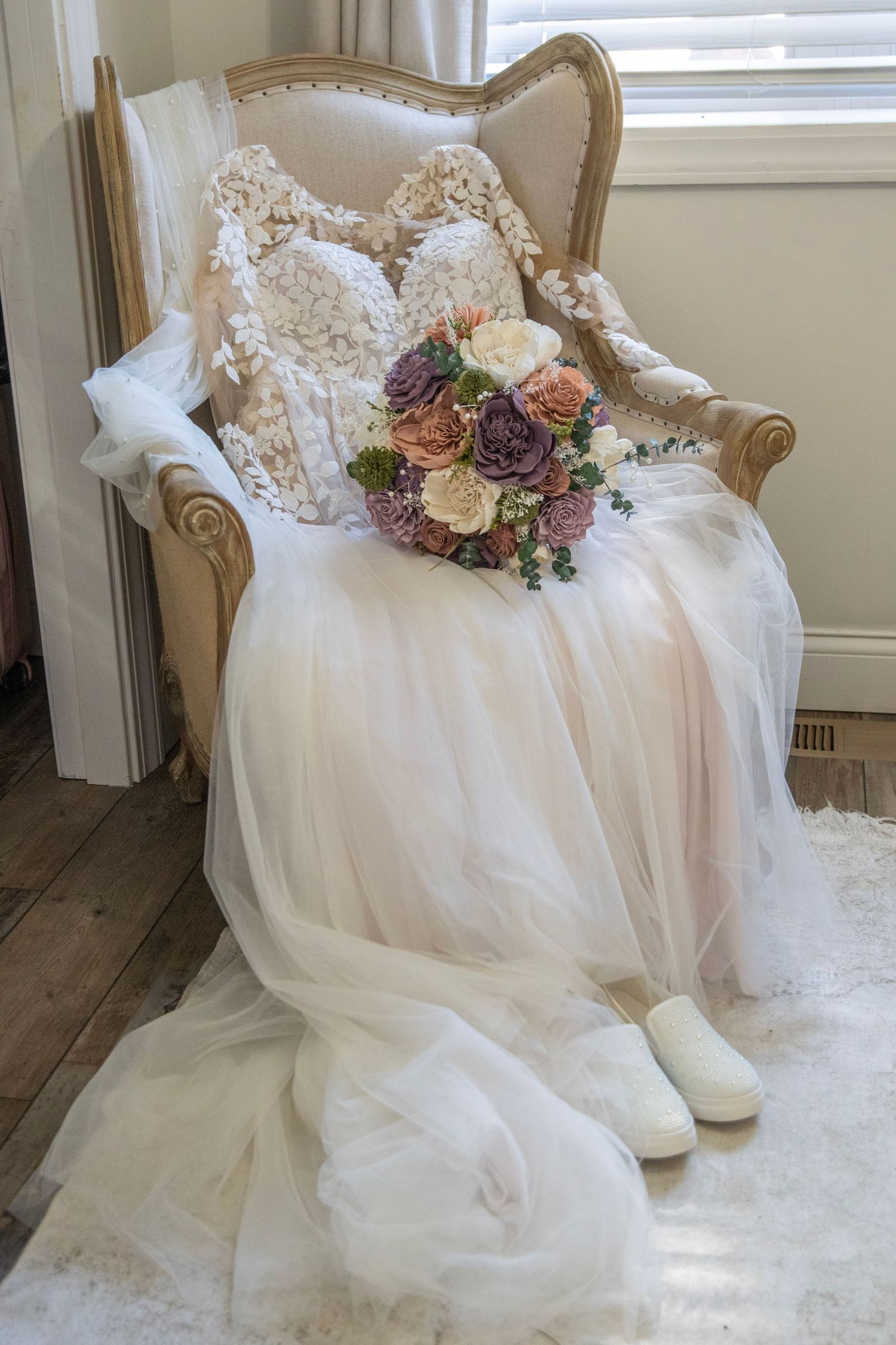 Elegant white wedding dress with floral details displayed on an ornate chair.