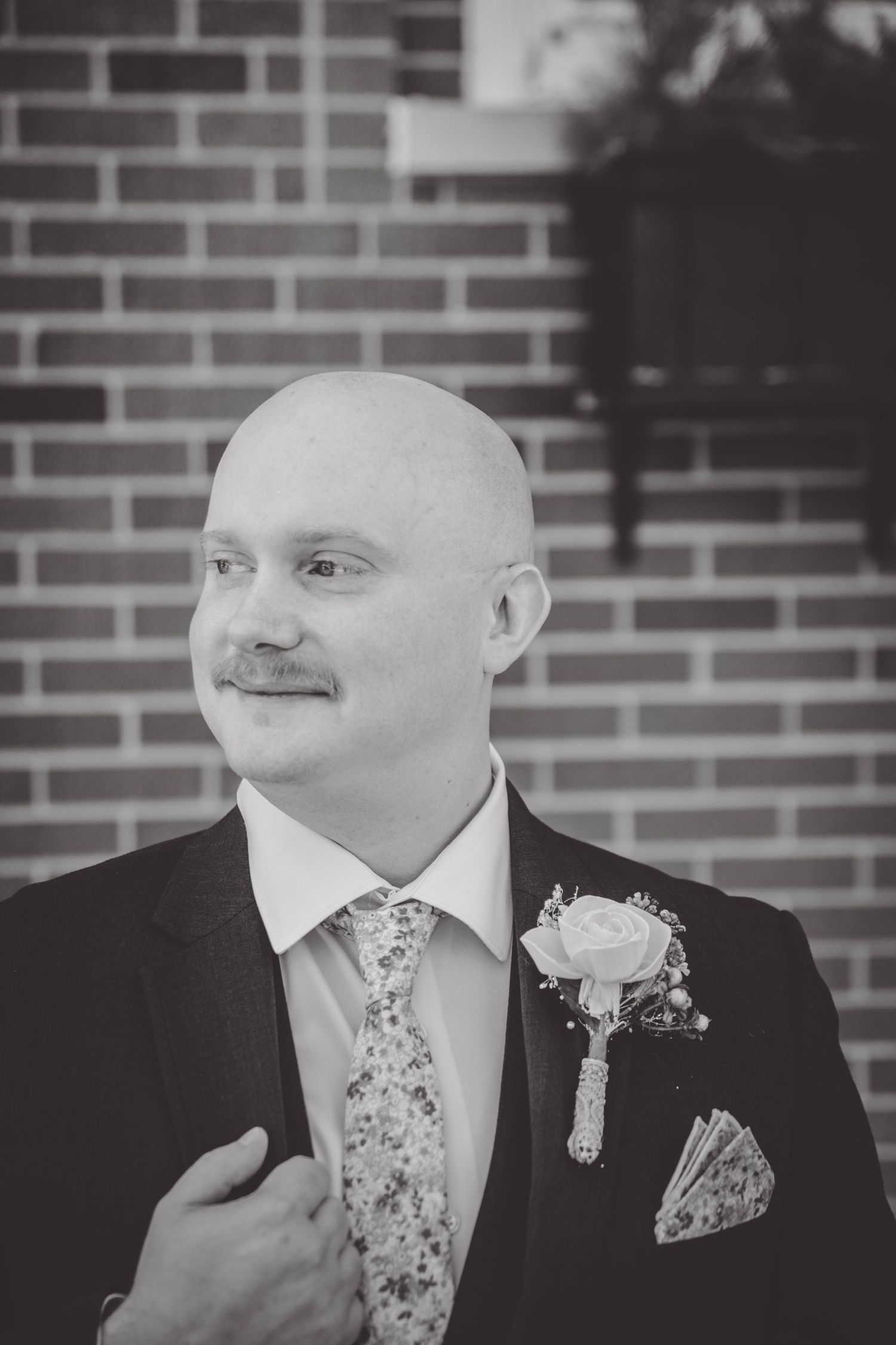 Black and white portraits of a groom wearing a boutonniere and patterned tie.