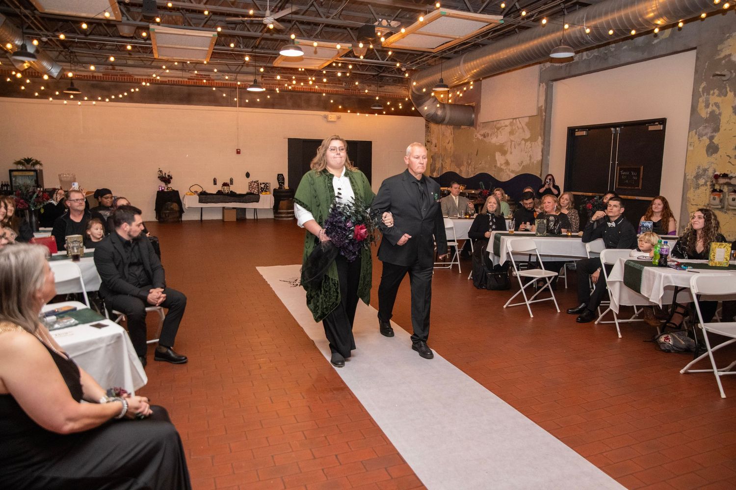 An indoor venue decorated with string lights and tables arranged for a special occasion.
