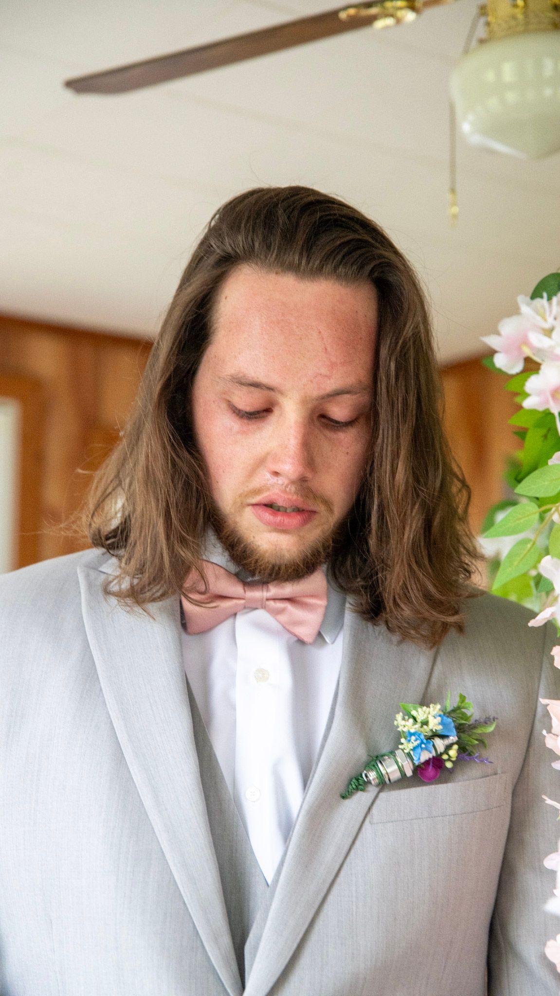 Groom in light gray suit with pink bow tie and floral boutonniere.