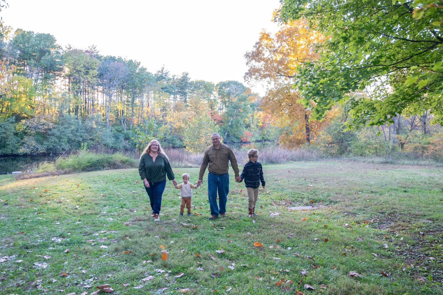 A group walking along a grassy hillside path during a beautiful fall afternoon.