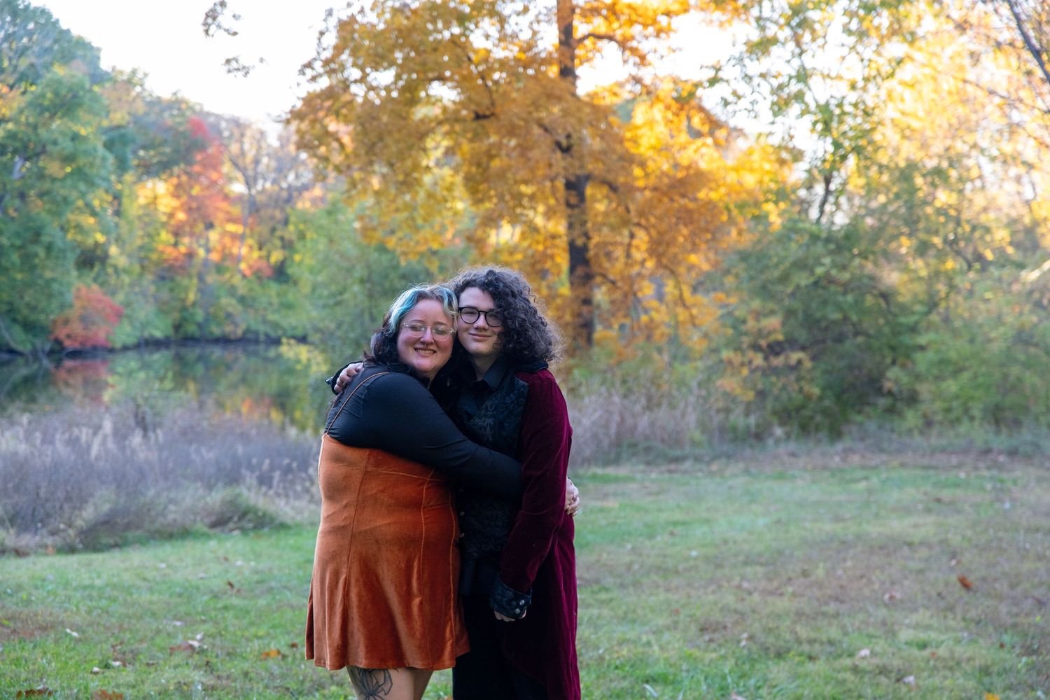 People stand together outdoors against a backdrop of golden autumn trees at sunset.