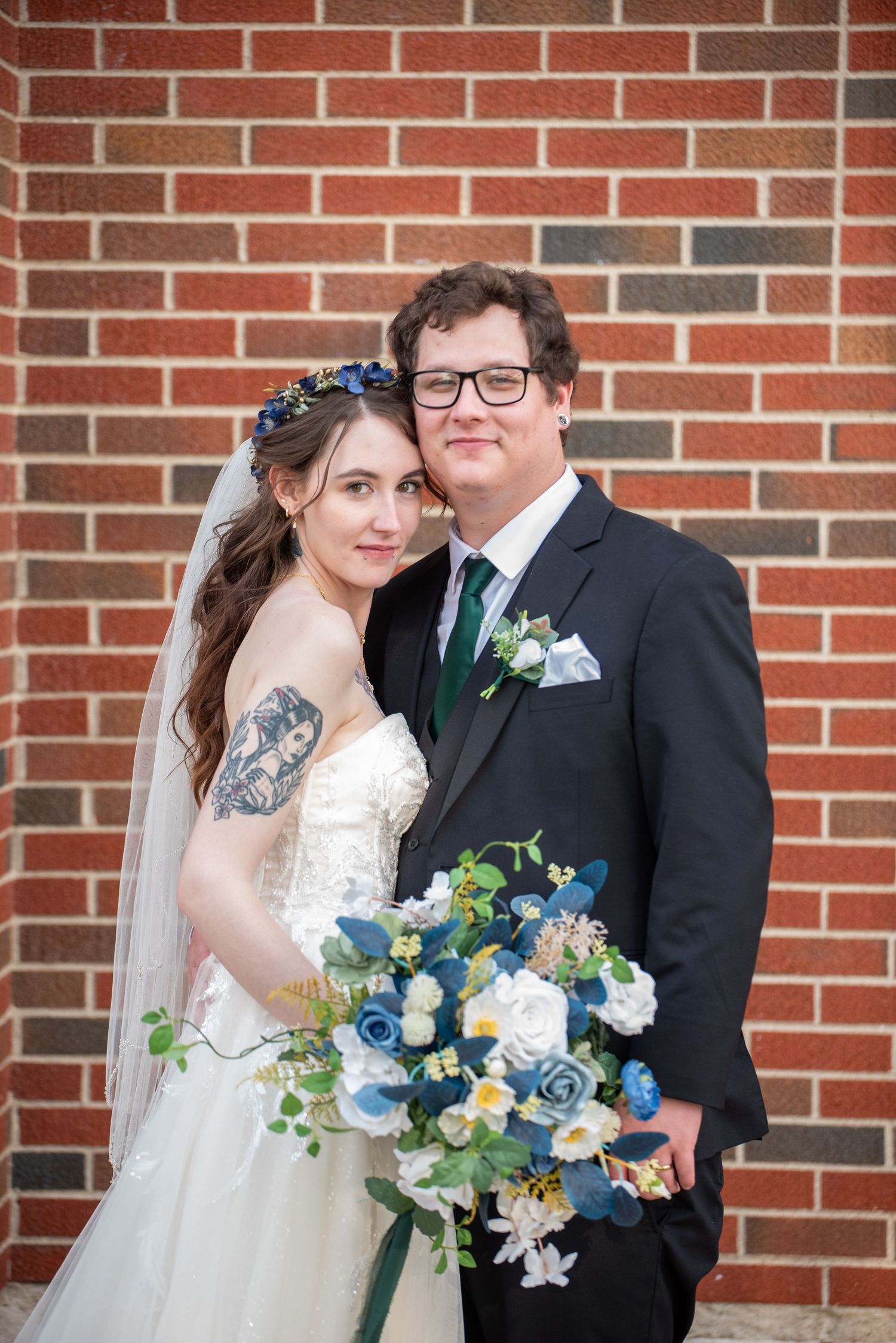 Wedding party portraits with blue and white floral bouquets against brick wall.