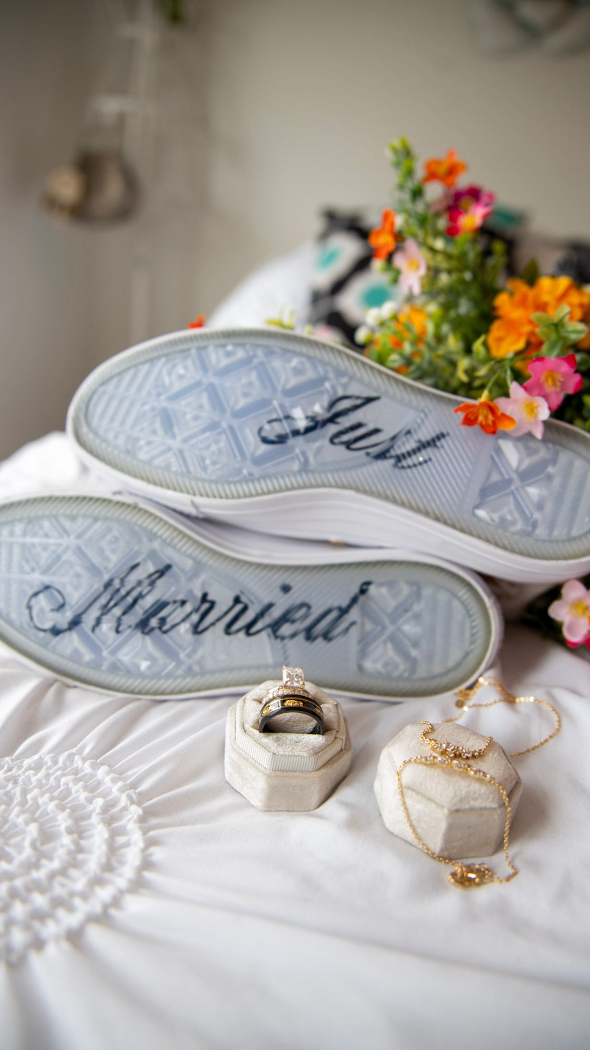 Wedding accessories including decorated shoes and jewelry arranged on white surface.